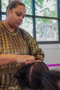 Woman braiding mannequin hair.